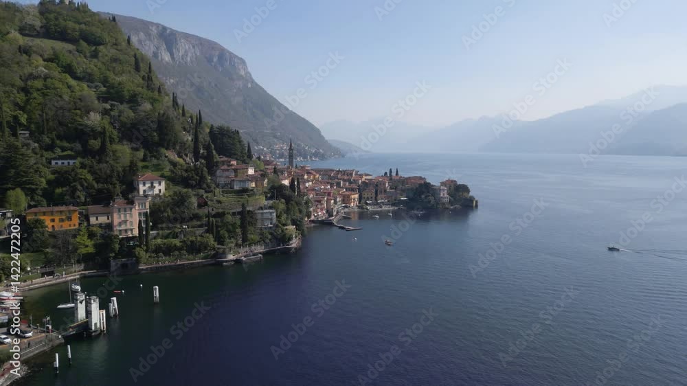 Aerial orbit view of Varenna during sunny afternoon from far, famous picturesque old town and turistic destination in Lake Como, Lombardy, Italy. Lake and mountains behind. Cinematic 4K drone shot. Aerial orbit view of Varenna during sunny afternoon from far, famous picturesque old town and turistic destination in Lake Como, Lombardy, Italy. Lake and mountains behind. Cinematic 4K drone shot.
