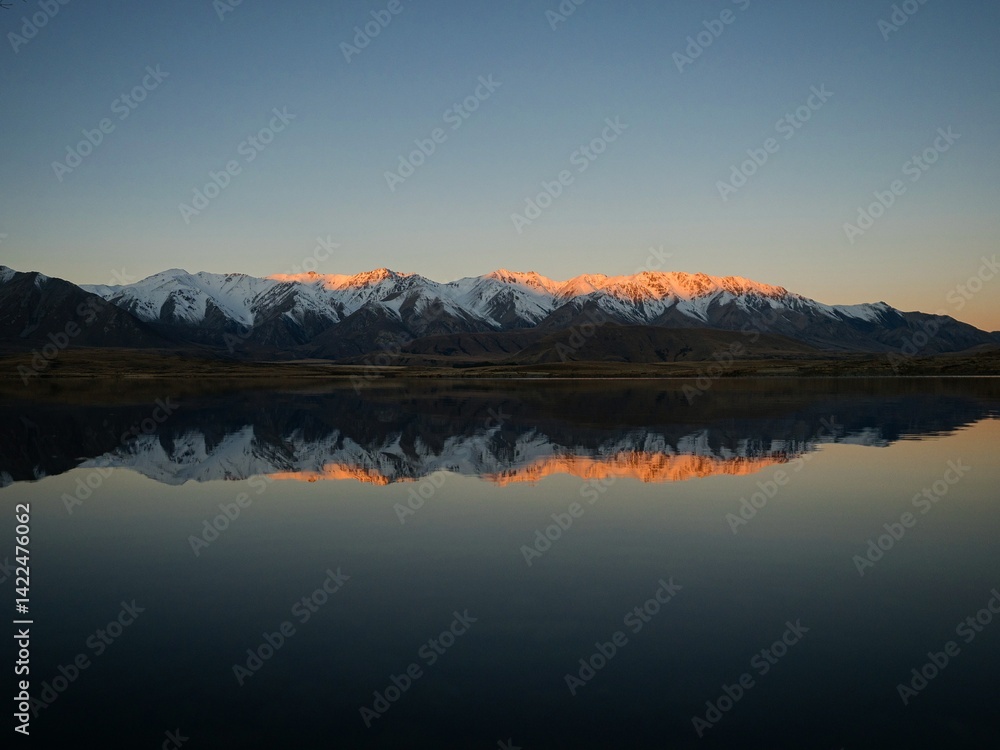 Fototapeta premium Lake Heron idyllic calm serene golden hour orange mountain peak winter sunset mirror reflection, Southern Alps landscape, Ashburton Lakes New Zealand