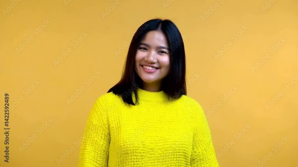 Smiling Woman in Yellow Sweater Making OK Hand Gesture on Yellow Background – Joyful Expression Smiling Woman in Yellow Sweater Making OK Hand Gesture on Yellow Background – Joyful Expression