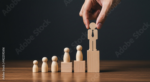 Hand placing wooden figure on top of blocks representing career growth and success on a wooden surface