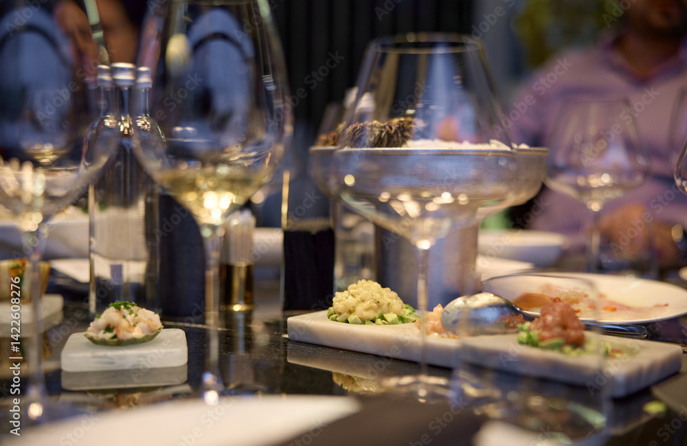 Naklejka premium Champagne tasting, Wine glasses are on the table, stylish table setting, wine is poured from a bottle and decanter, sparkling wine bubbles, snacks, people smell the aroma and taste the wine