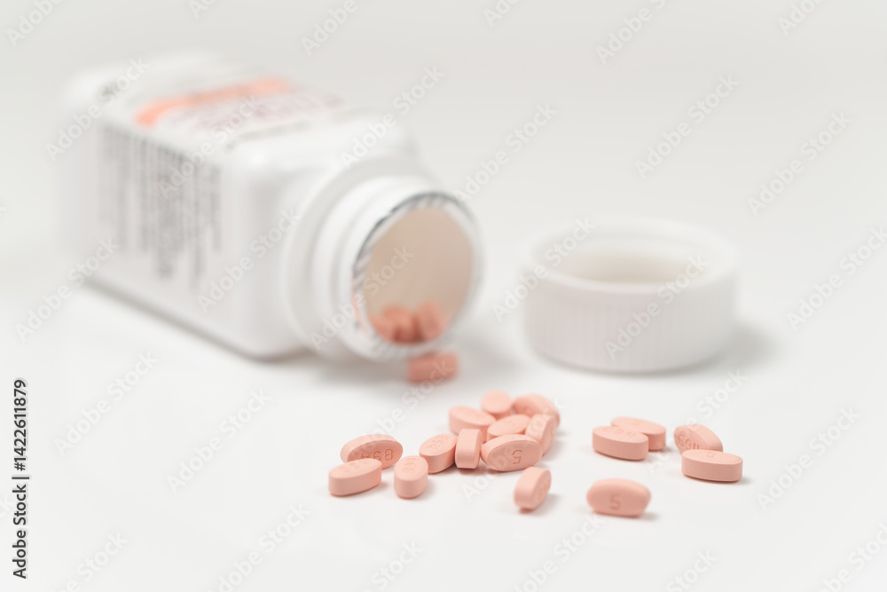 Yellow pills spilling out of medicine bottle
