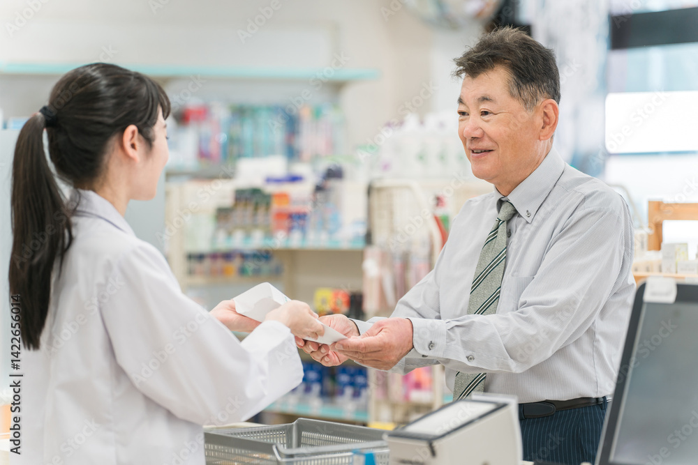 Obraz premium 薬局,ドラックストアのレジで処方箋の説明を受けるシニア男性 