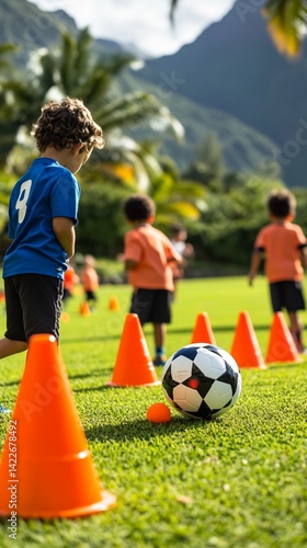 Young soccer player training on lush green field with orange cones, focusing on skill development during dynamic outdoor practice session with mountain backdrop
