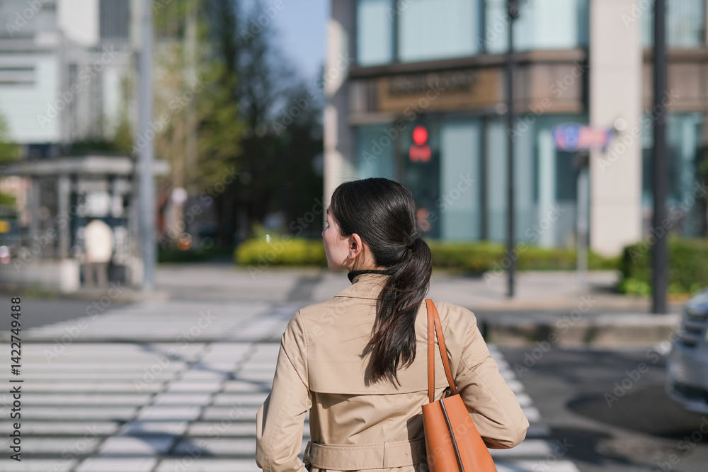 Fototapeta premium 新緑の丸の内を歩くビジネスウーマンの後ろ姿