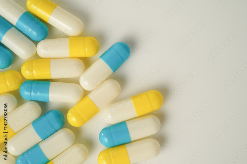 Capsules pill white blue yellow scattered on white surface, health care, medical background Capsules pill white blue yellow scattered on white surface, health care, medical background