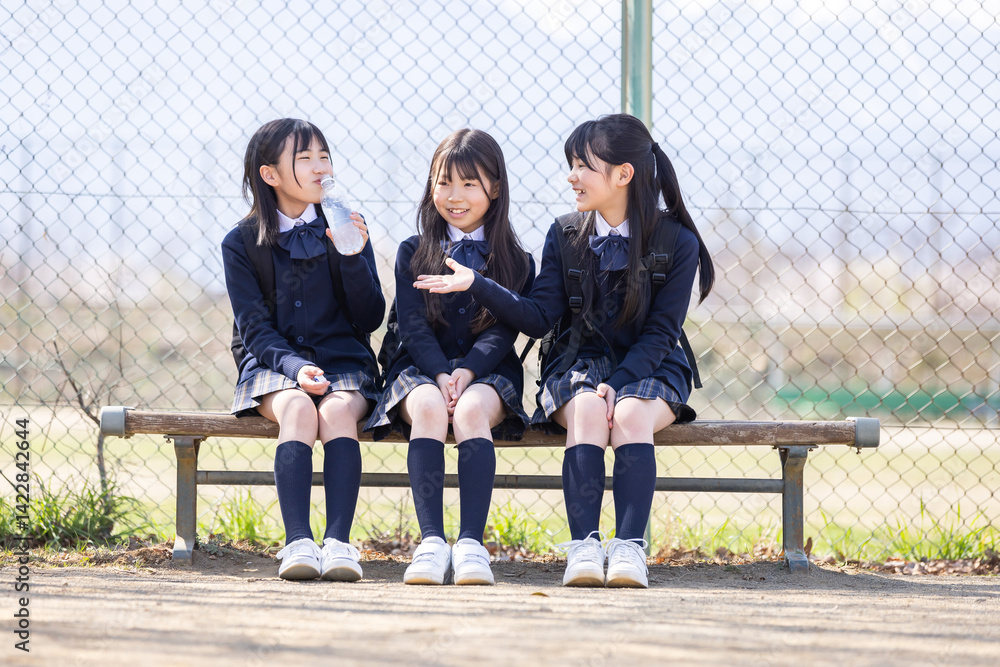グラウンドのベンチに座る女子学生