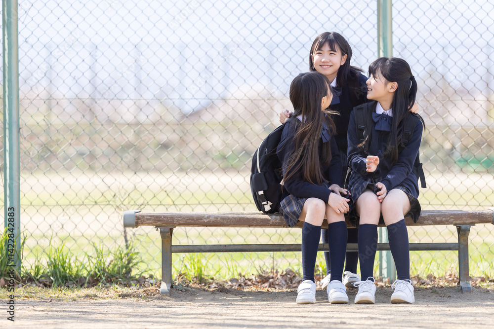 グラウンドのベンチに座る女子学生