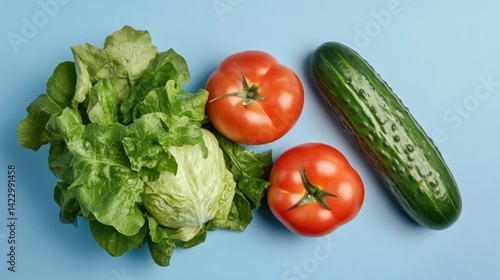 Healthy and raw vegetables including cucumbers and tomatoes on light blue table for vegan meals