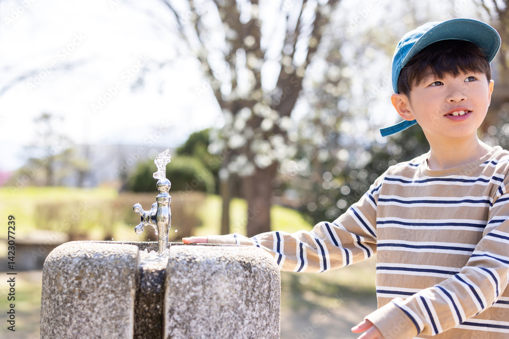 公園の水道で水を飲む男の子