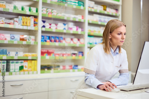 Focused Female Pharmacist Working on Computer in a Well-Organized Pharmacy Free Download Focused Female Pharmacist Working on Computer in a Well-Organized Pharmacy - GFXLoad