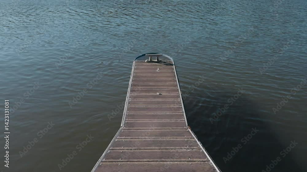 Long wooden dock extending into still waters under daylight with serene reflections Long wooden dock extending into still waters under daylight with serene reflections