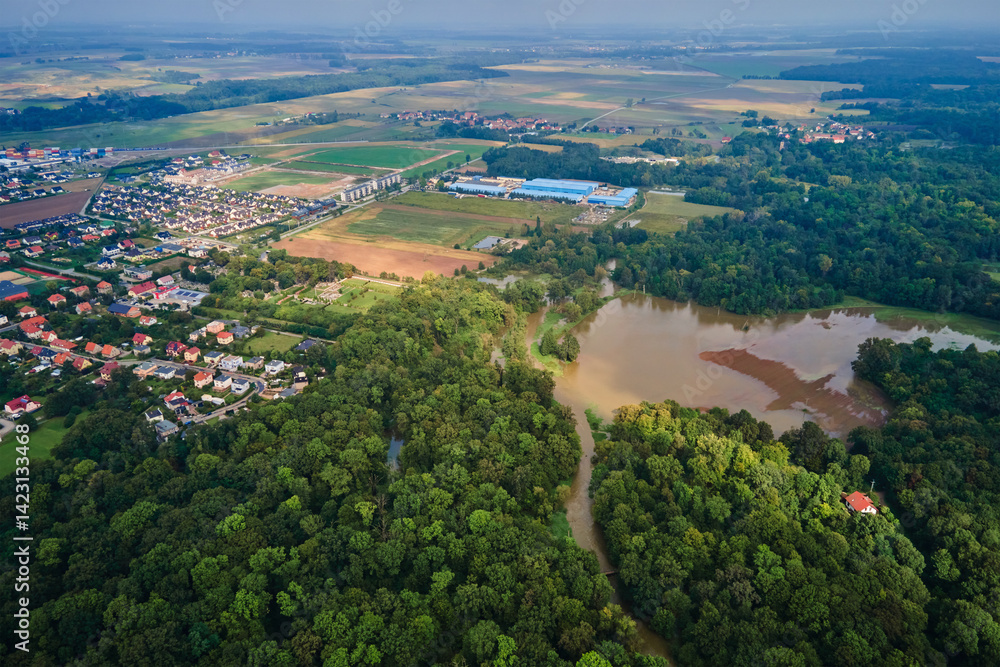 Aerial view of flooded landscape with rural village, farmlands and forest. Natural disaster