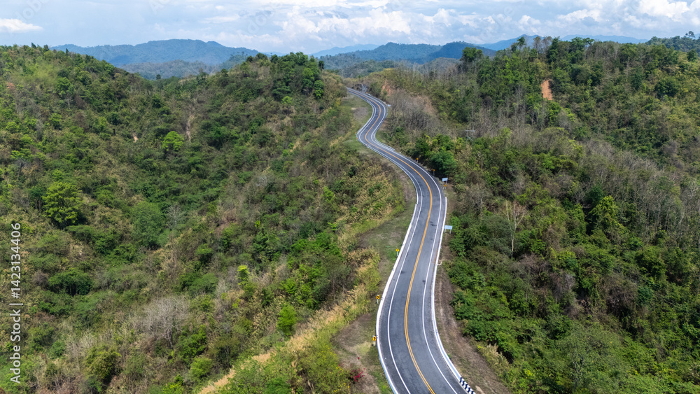 A winding road meanders through lush green hills, surrounded by dense forests under a bright blue sky, showcasing a scenic view of nature. A winding road meanders through lush green hills, surrounded by dense forests under a bright blue sky, showcasing a scenic view of nature.