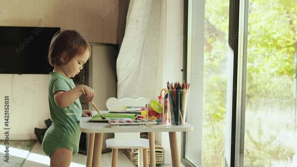 A child happily plays at a sunny table with art supplies, in front of a large window in a sunny room in a tiny house, exploring his imagination and creativity. A child happily plays at a sunny table with art supplies, in front of a large window in a sunny room in a tiny house, exploring his imagination and creativity.