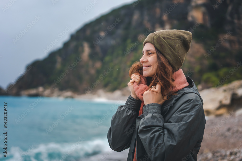 Young relaxed woman enjoying sea breeze in rainy weather