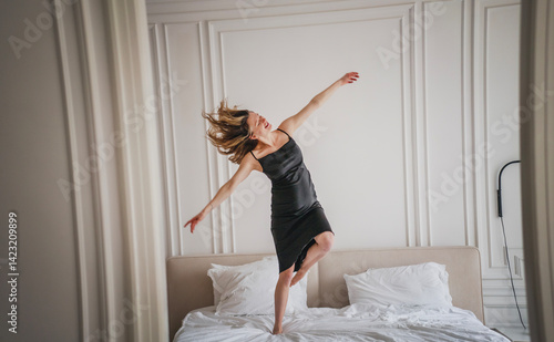 Obraz na płótnie Young caucasian european happy woman in black slip dress dancing on bed, beauty fashion concept w salonie