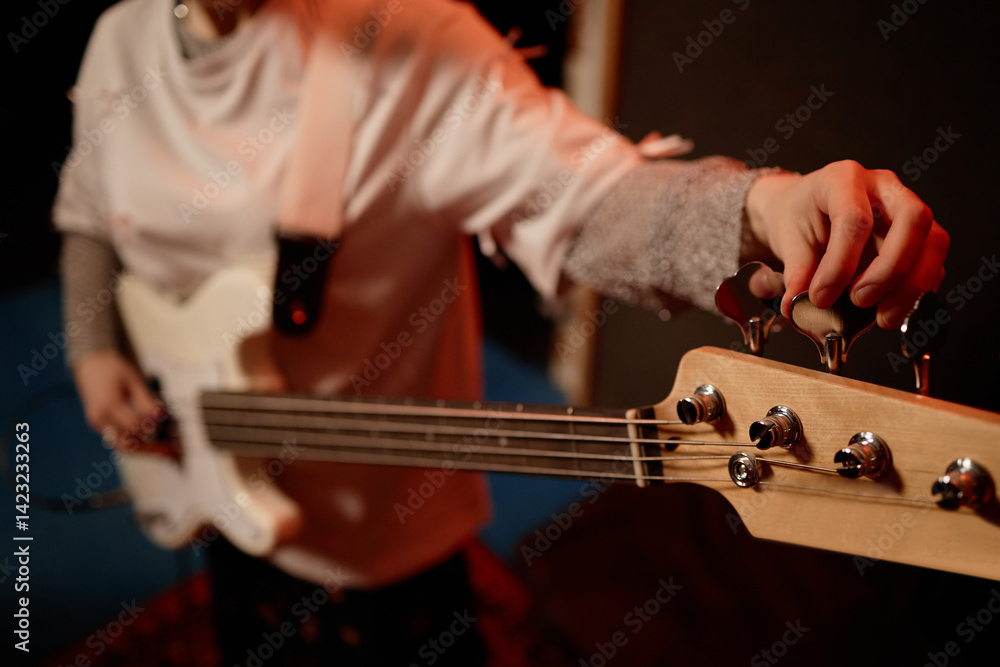 Φωτογραφία Close up on hand of female musician adjusting tuning pegs of electing bass guita