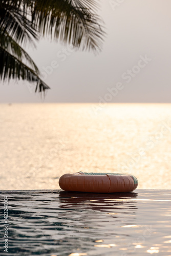 Obraz na płótnie Inflatable circle floats on the pool at sunset, Surround tropical decor and greenery palm tree, Relaxing summer holiday, Inflatable ring float on water sunset view, Summer background vacation leisure. w salonie