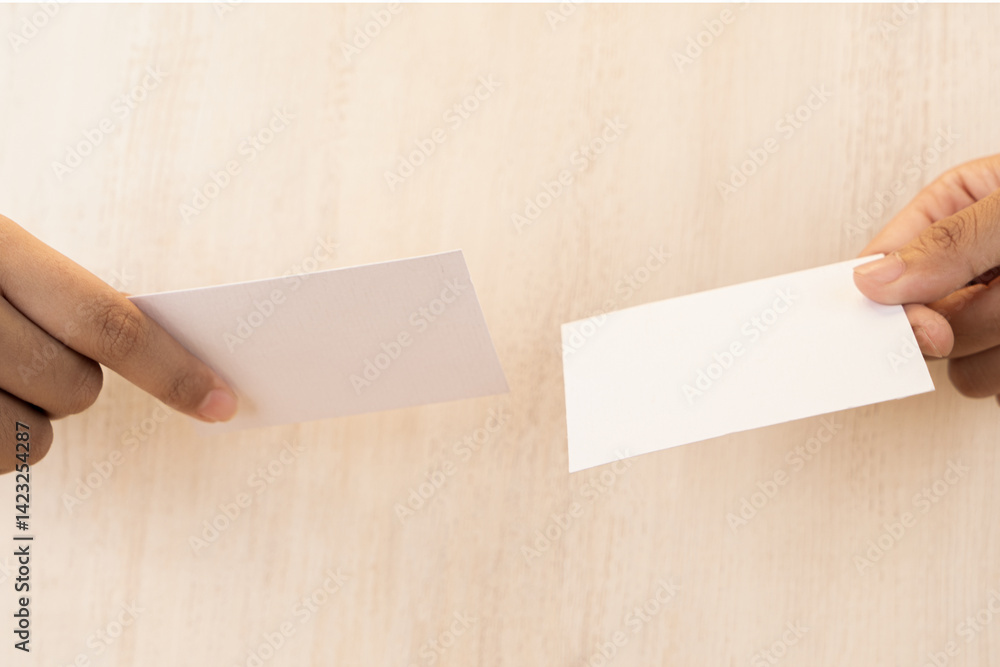 Obraz premium Hand holding white blank business card mockup on wooden background