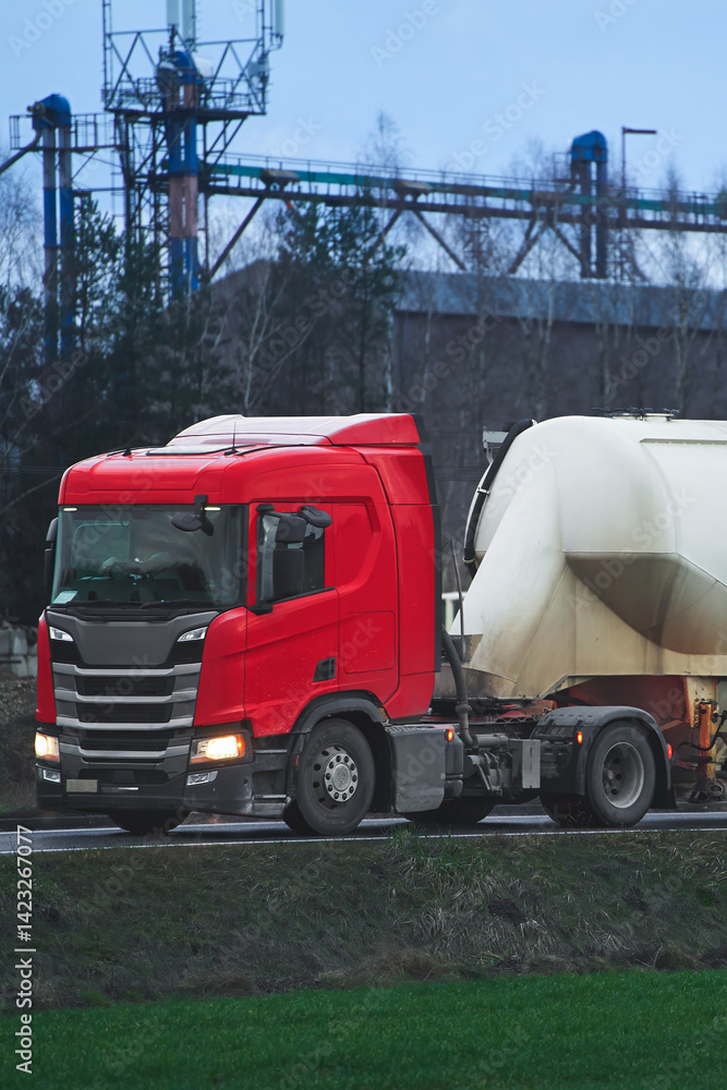 Red semi-truck pulling a white cylindrical tanker
