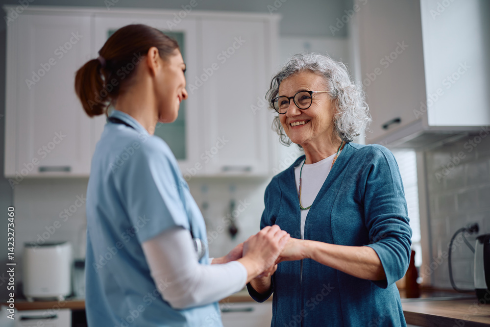 Obraz premium Happy senior woman holding hands with homecare nurse during visit.