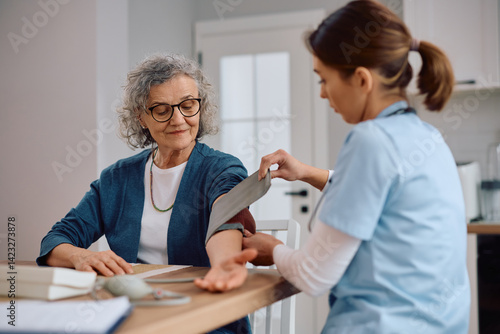 Senior woman getting her blood pressure measured by homecare nurse.