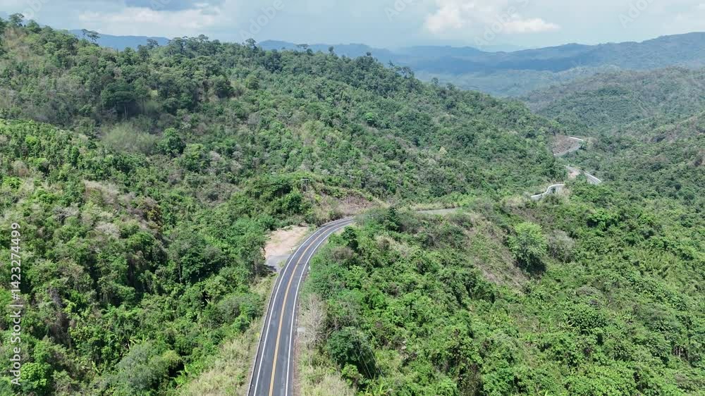 Aerial view highway Drone flying above winding road during sunlight, Winding asphalt road through tropical rainforest. countryside landscape. Landmark tourist attractions in Nan Province, Thailand. Aerial view highway Drone flying above winding road during sunlight, Winding asphalt road through tropical rainforest. countryside landscape. Landmark tourist attractions in Nan Province, Thailand.