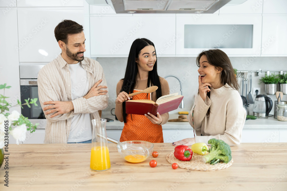 Fototapeta premium Three friends gather around a cookbook in a cozy kitchen, sharing laughs and ideas to create a delicious meal together.