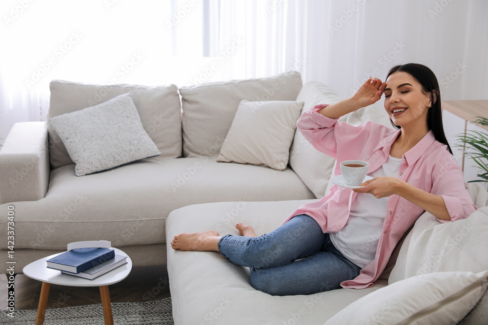 Woman with cup of drink resting on sofa in living room Woman with cup of drink resting on sofa in living room