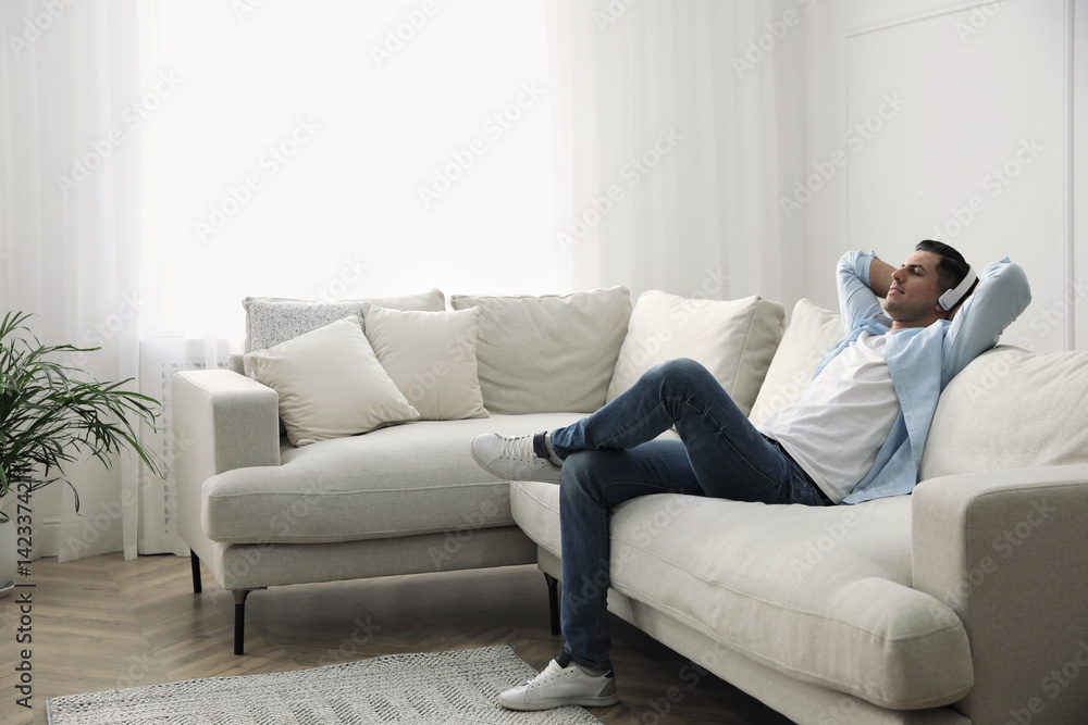 Man with headphones sitting on comfortable sofa in living room Man with headphones sitting on comfortable sofa in living room