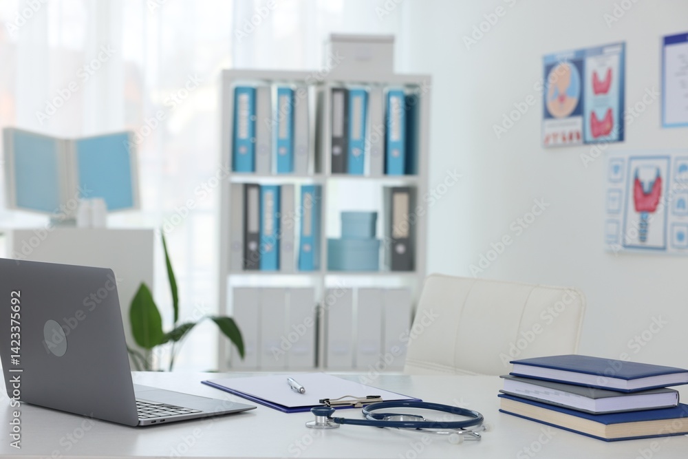 Laptop, stationery and stethoscope on desk in doctor's office