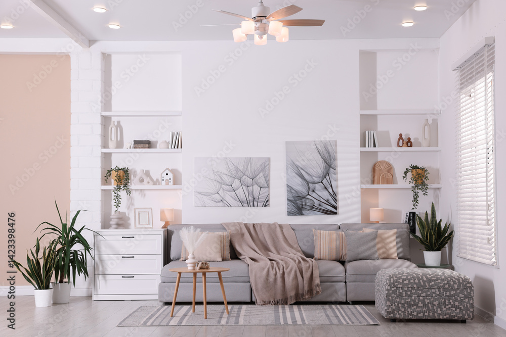 Fototapeta premium Comfortable sofa, houseplants and decorative elements in living room. Interior design