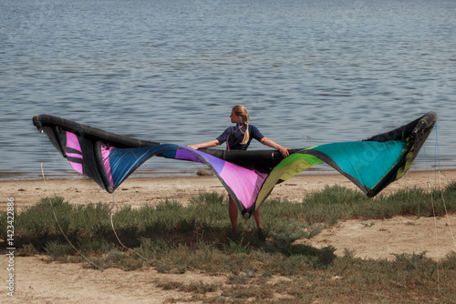 A woman with a multicolored parachute, an athlete riding kitersurfing on a blue pore. Beach, active recreation. Sunset competitions, parachute, board, freedom. High quality photo