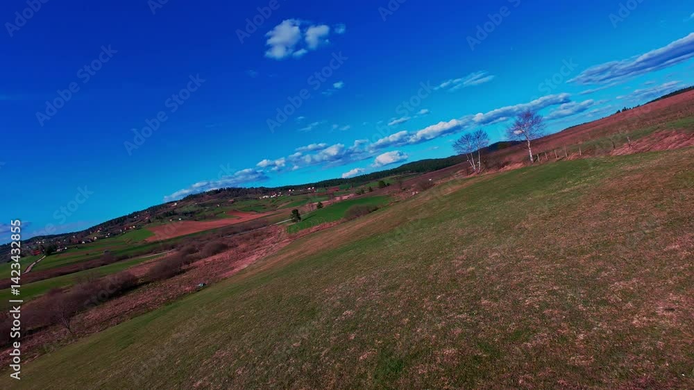 Vertical video FPV drone view banking over vibrant green fields and rolling countryside under bright blue sky with scattered clouds. Scenic rural landscape, fast motion, dynamic aerial fpv drone Vertical video FPV drone view banking over vibrant green fields and rolling countryside under bright blue sky with scattered clouds. Scenic rural landscape, fast motion, dynamic aerial fpv drone