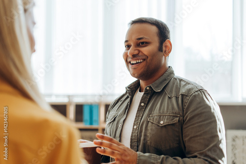 Φωτογραφία Indian businessman holding coffee cup talking with colleague in office