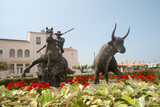 Statue of man in hat riding horse near bull in sunlight, Les Saintes Maries de la Mer Camargue, France