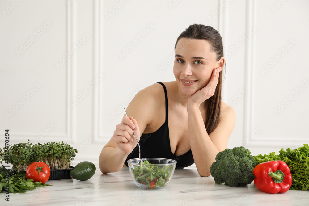 Woman in fitness clothes with salad at white marble table indoors. Healthy food
