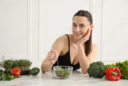 Obraz na płótnie Woman in fitness clothes with salad at white marble table indoors. Healthy food w salonie