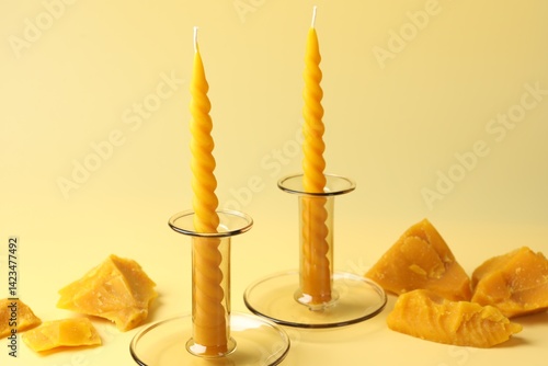 Obraz na płótnie Beeswax candles in candlesticks and wax pieces on beige background, closeup w salonie