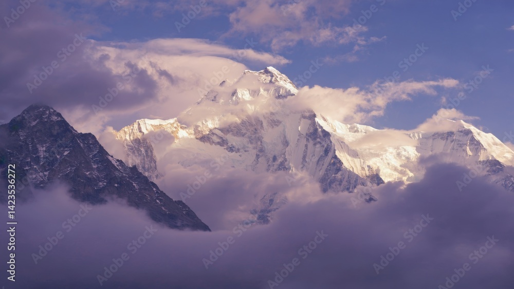 Sunlight and clouds illuminating a majestic mountain peak, possibly Everest. Sunlight and clouds illuminating a majestic mountain peak, possibly Everest.