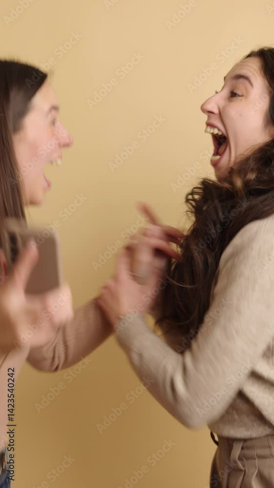 Two friends reacting to surprising news on phone joyfully Two friends reacting to surprising news on phone joyfully