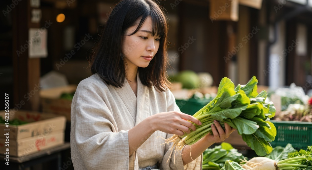 Obraz premium Woman holds leafy greens at outdoor market stall with wooden crates.