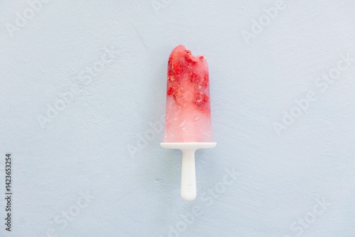Red popsicle on pastel blue background.