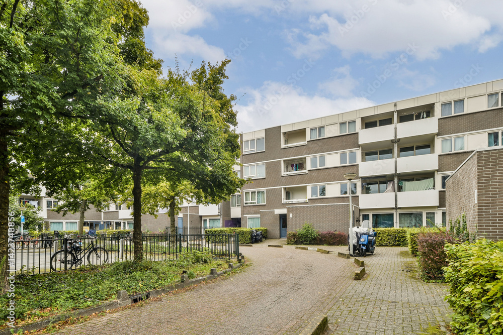 A contemporary apartment building showcases a blend of architecture and nature, framed by lush trees and well-maintained paths for residents. A contemporary apartment building showcases a blend of architecture and nature, framed by lush trees and well-maintained paths for residents.