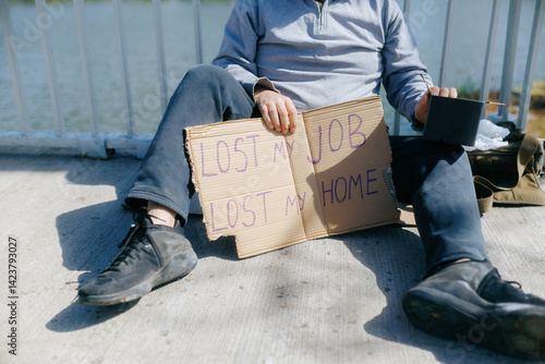 Man sits by the waterfront holding a sign about his struggles