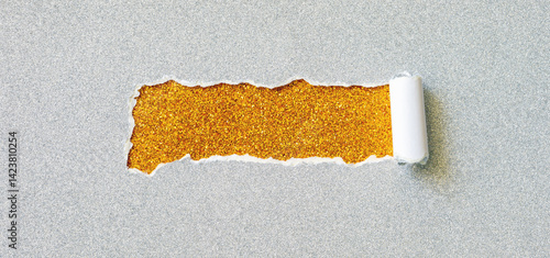 Photography Piece of torn silver glitter paper exposes a radiant gold surface beneath with r