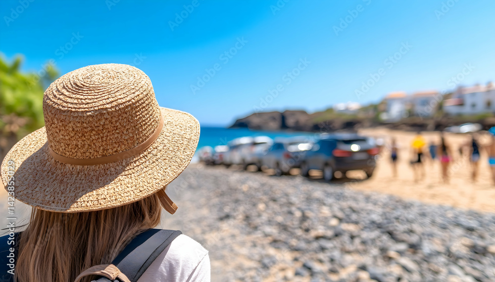 Fototapeta premium Woman in straw hat walks towards a beach with parked cars and people