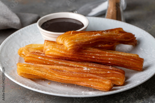 Obraz na płótnie Traditional Spanish treat street fast food churros on a plate with hot chocolate sauce. w salonie