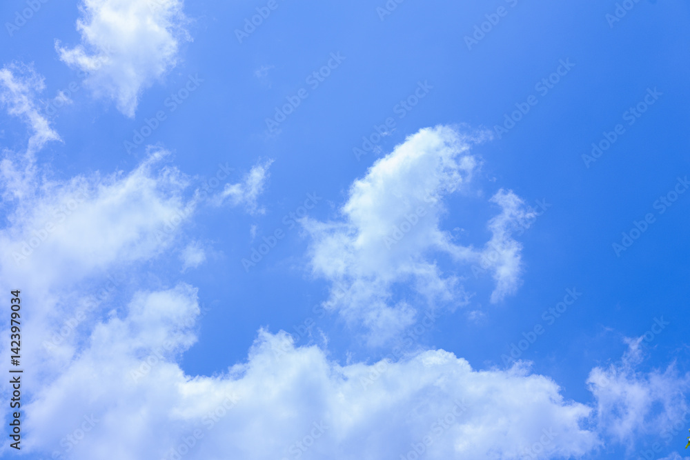 Obraz premium Fluffy Clouds Against a Vibrant Blue Sky